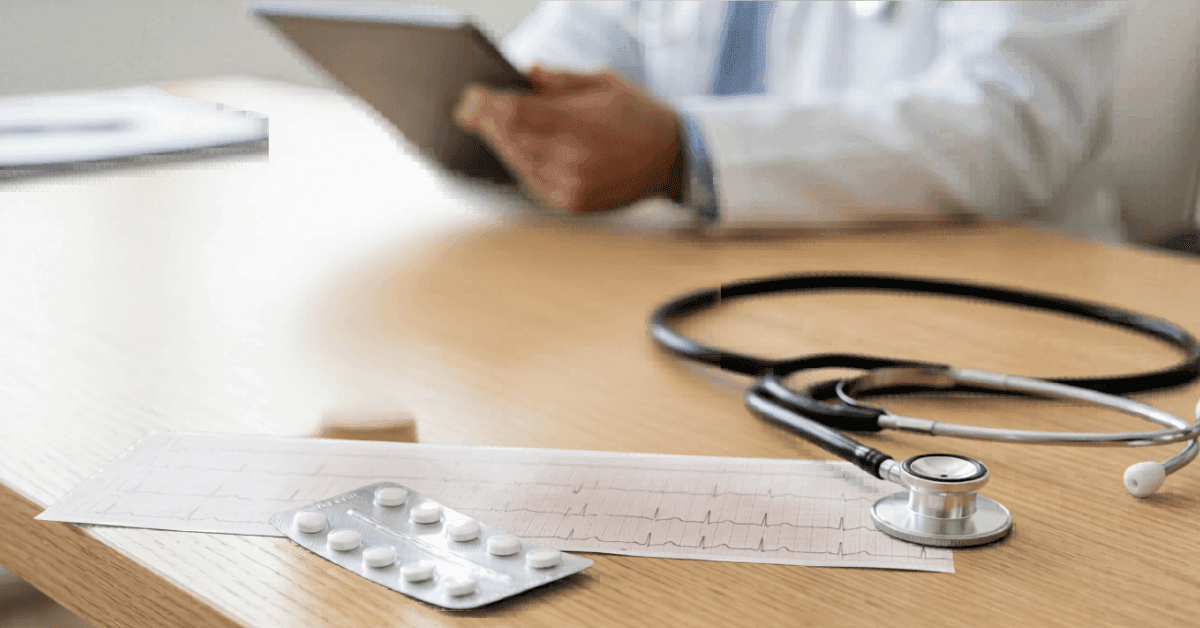 Ecosprin 150 Aspirin 150mg blister pack on GP desk with ECG report and stethoscope